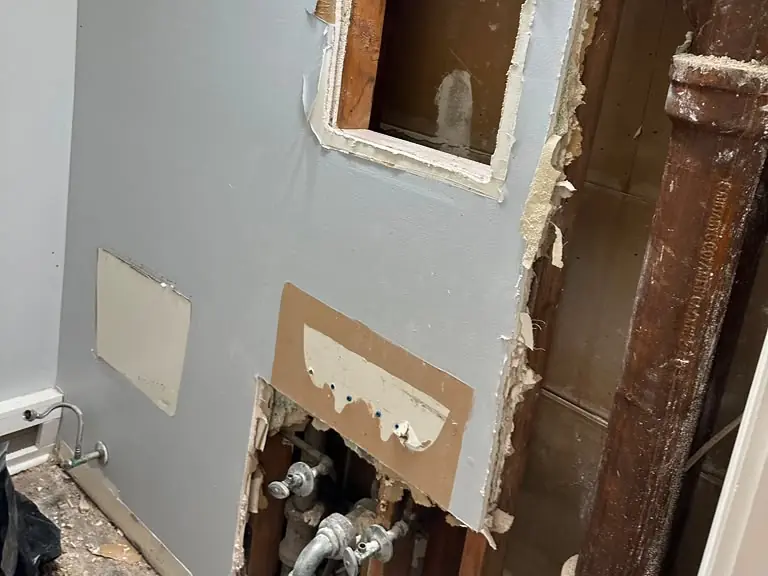 Bathroom wall access cut to expose leaking supply valves and the cast-iron stack for repair — leak detection and repair in Nutley, NJ