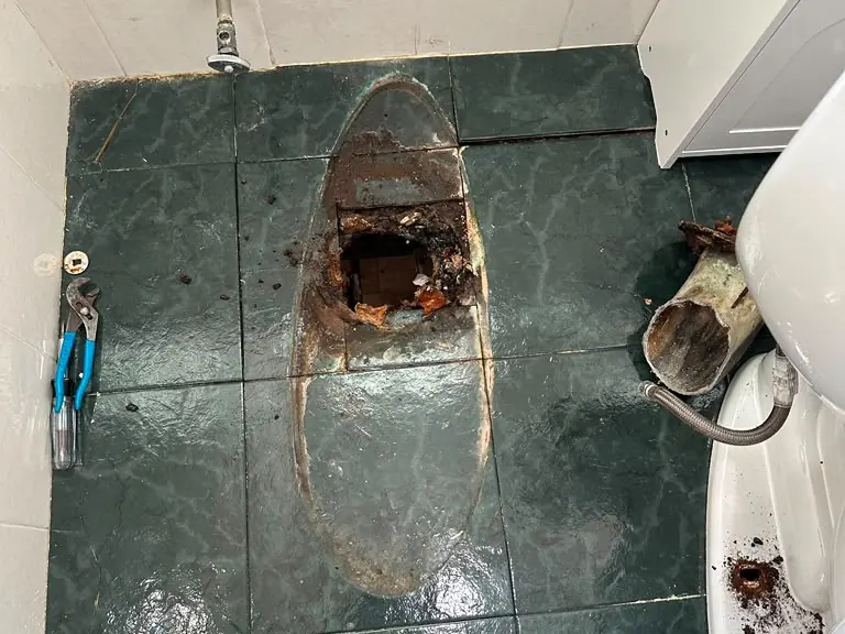 Broken, corroded toilet flange and rotted subfloor exposed before repair — toilet repair in Northern New Jersey