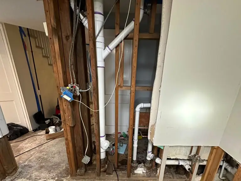 Burst pipe damage replumbed with new PVC drain and vent lines in the open wall framing — broken pipe repair in Central New Jersey