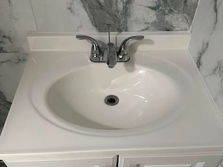 Chrome centerset bathroom faucet installed on a white vanity with marble walls — faucet installation in Northern New Jersey