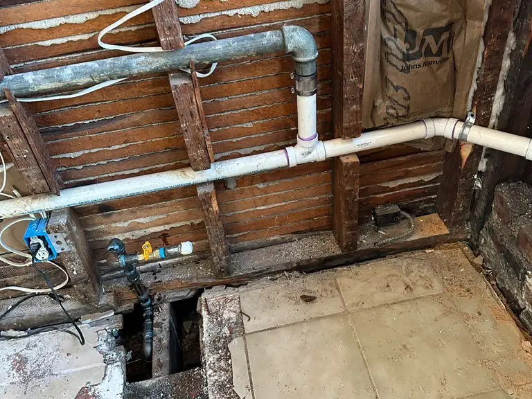 Old galvanized drain replaced with new PVC piping in an opened wall and floor — broken pipe repair in South Jersey