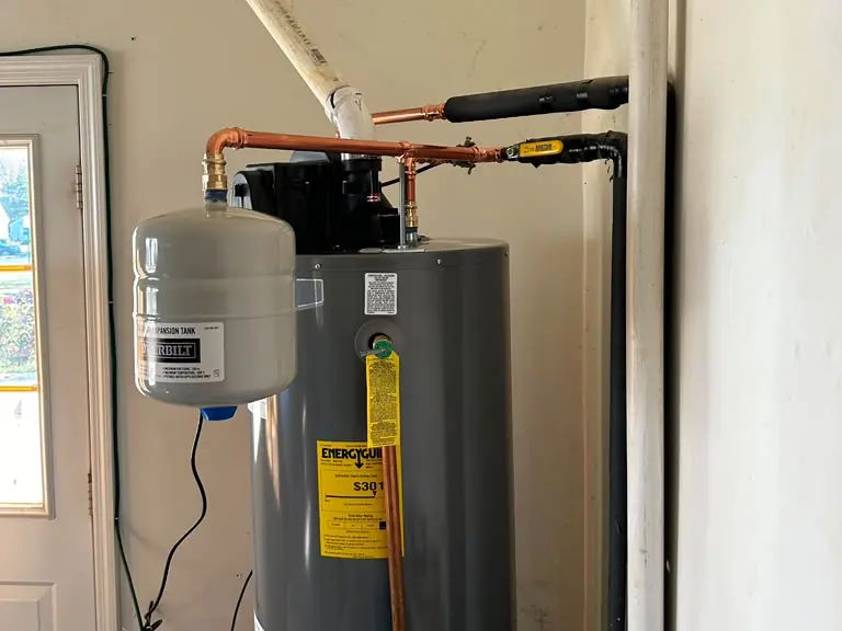 Water heater installed in a garage with new expansion tank, copper lines and PVC vent — water heater installation and repair in Bedminster, NJ