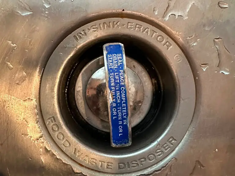 Garbage disposal sink flange and splash guard in a stainless steel kitchen sink — garbage disposal service in New Jersey