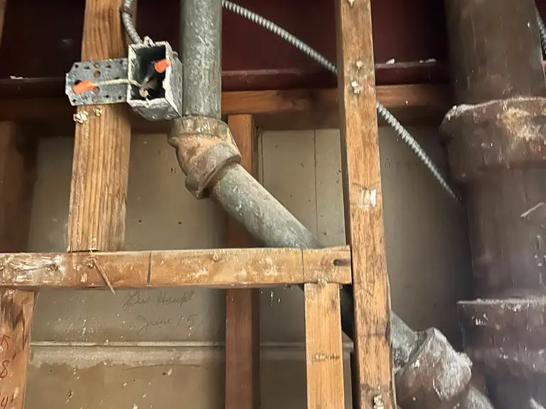 Wall opened to trace a hidden leak on old galvanized and cast-iron drain piping — leak detection and repair in Berlin, NJ