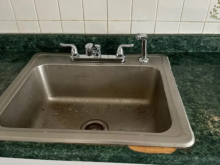 Replacement chrome kitchen faucet with side sprayer installed on a stainless sink — faucet installation in New Jersey