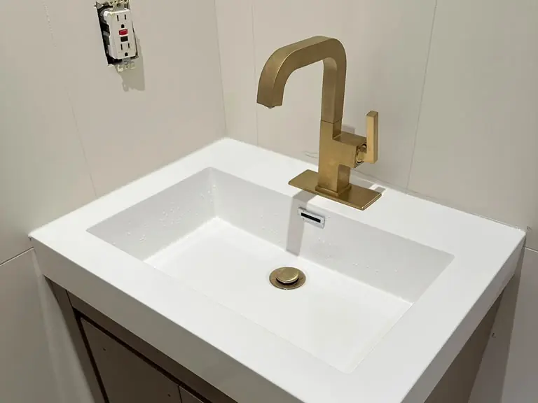 Modern gold bathroom faucet installed on a new vanity — Lumin Drain NJ