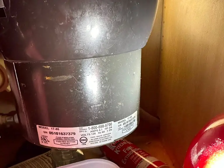 Aging garbage disposal unit under the sink being evaluated for replacement — garbage disposal service in New Jersey
