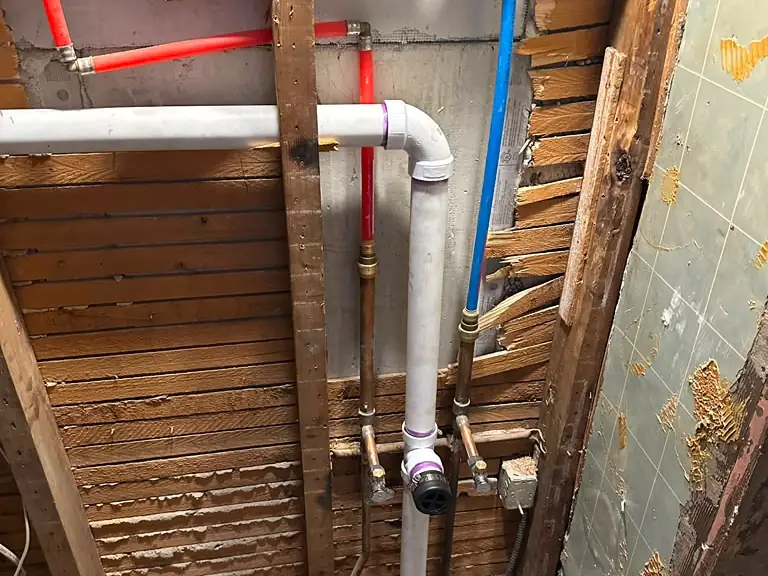 New PEX supply lines and PVC drain installed in an opened wall — Lumin Drain NJ