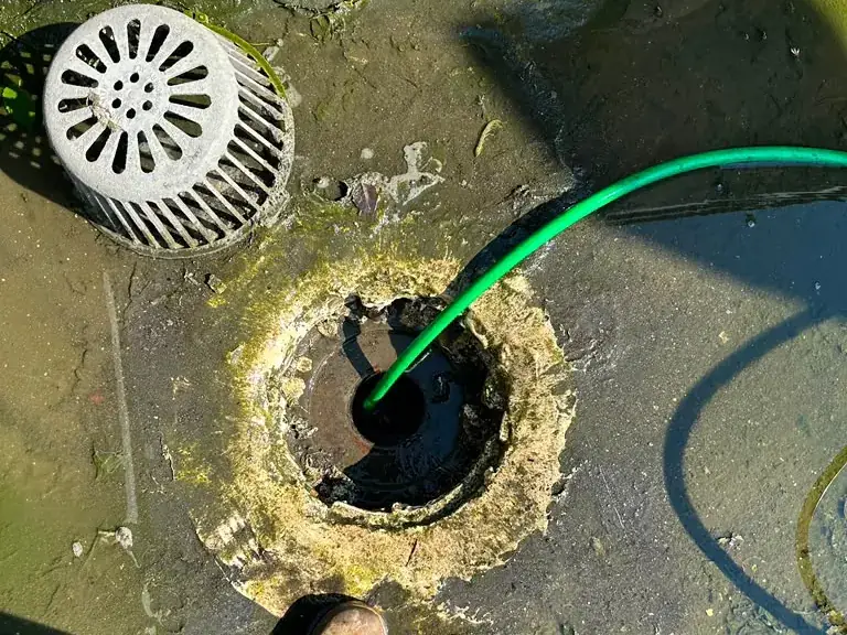 Hydro jetting hose clearing a clogged flat roof drain next to the strainer dome — hydro jetting in Allamuchy, NJ