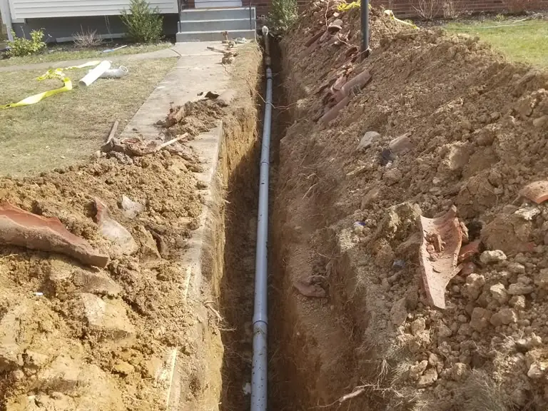 Full sewer line replacement trench running from the house toward the street in a front yard — sewer line repair in Montclair, NJ